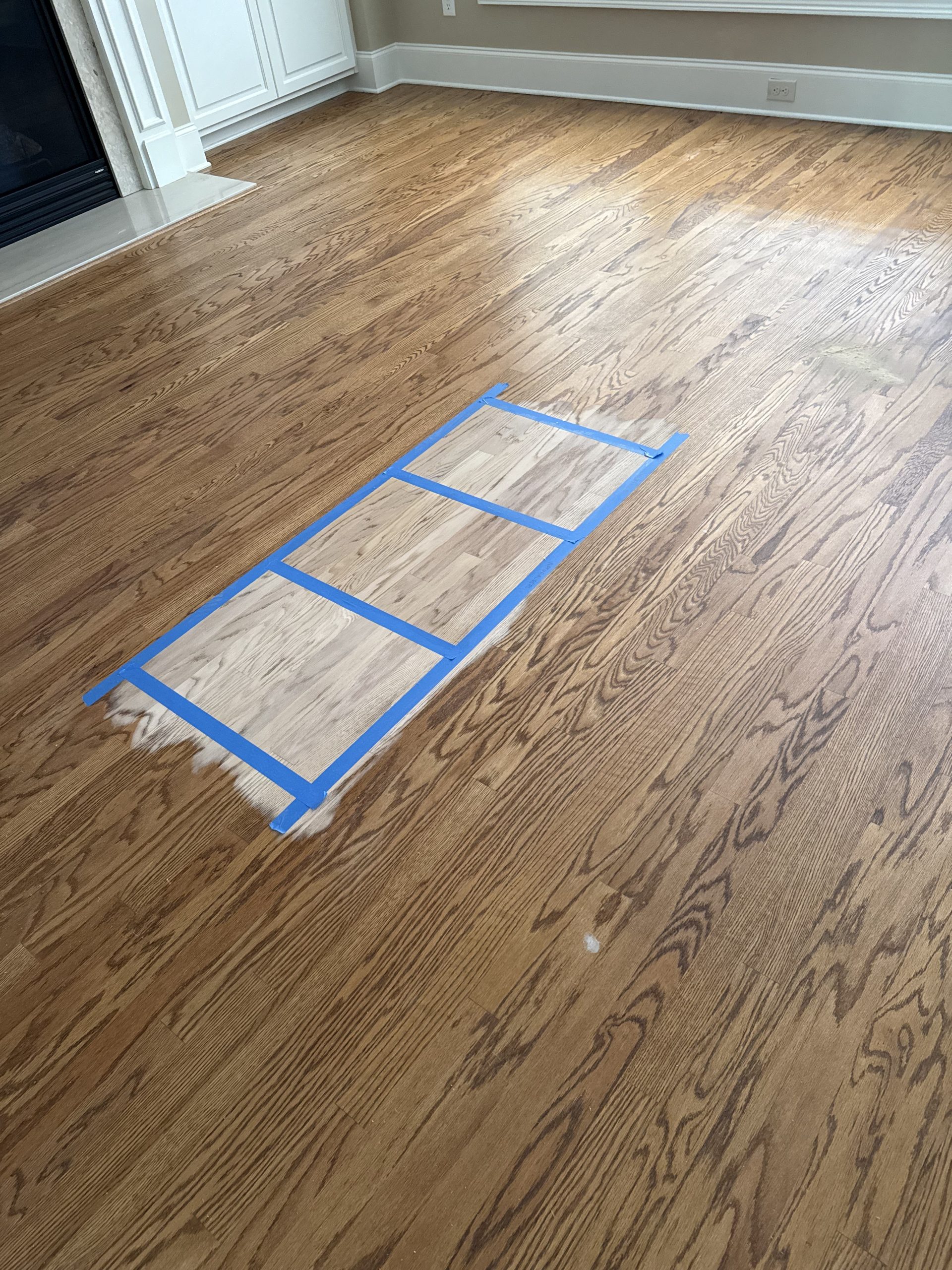 Stain samples taped onto a customer's own red oak floor to compare colors