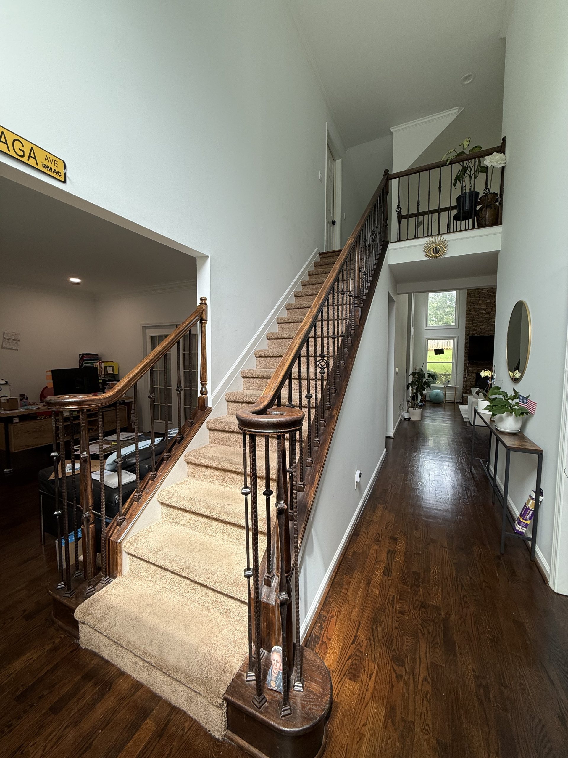 Two-story foyer with dark refinished hardwood flooring and a carpeted stair runner