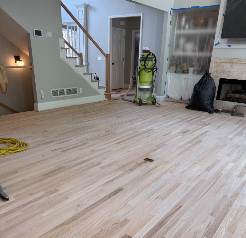 Hardwood floor sanding in progress in an Alpharetta home — red oak sanded to bare wood with a dust-containment vacuum rig