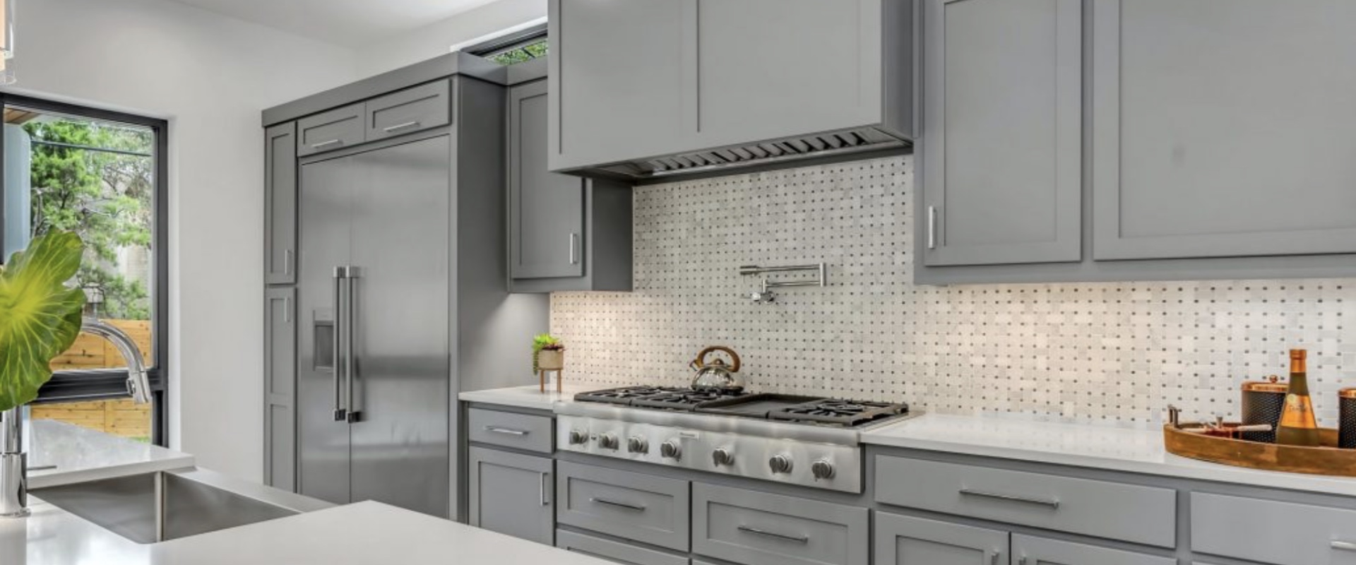 Remodeled kitchen with gray shaker cabinets, quartz countertops, and basketweave marble backsplash in Alpharetta GA