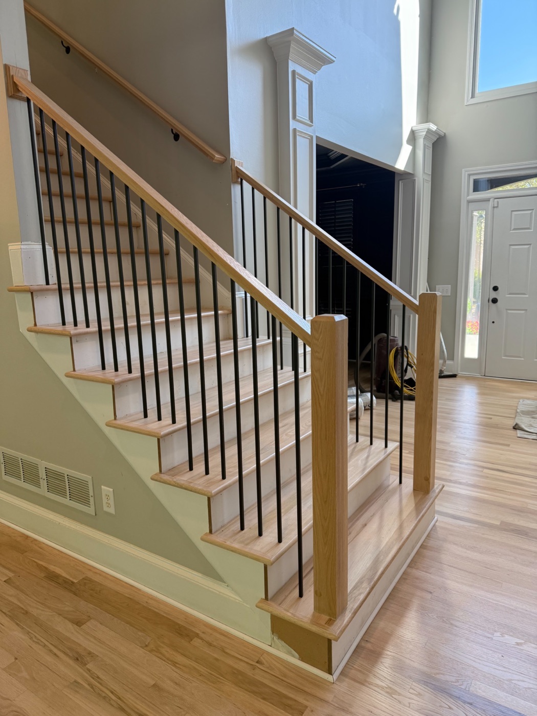 Stair remodel with stained oak treads, white risers, and iron balusters