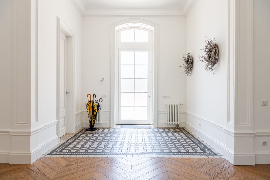 Bright foyer showcasing sophisticated interior design with parquet flooring and decor elements.