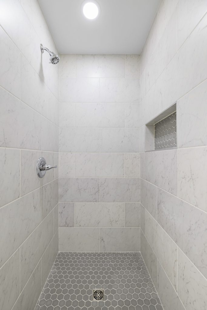 Explore a modern minimalist shower interior with sleek gray tiles and a contemporary showerhead design.