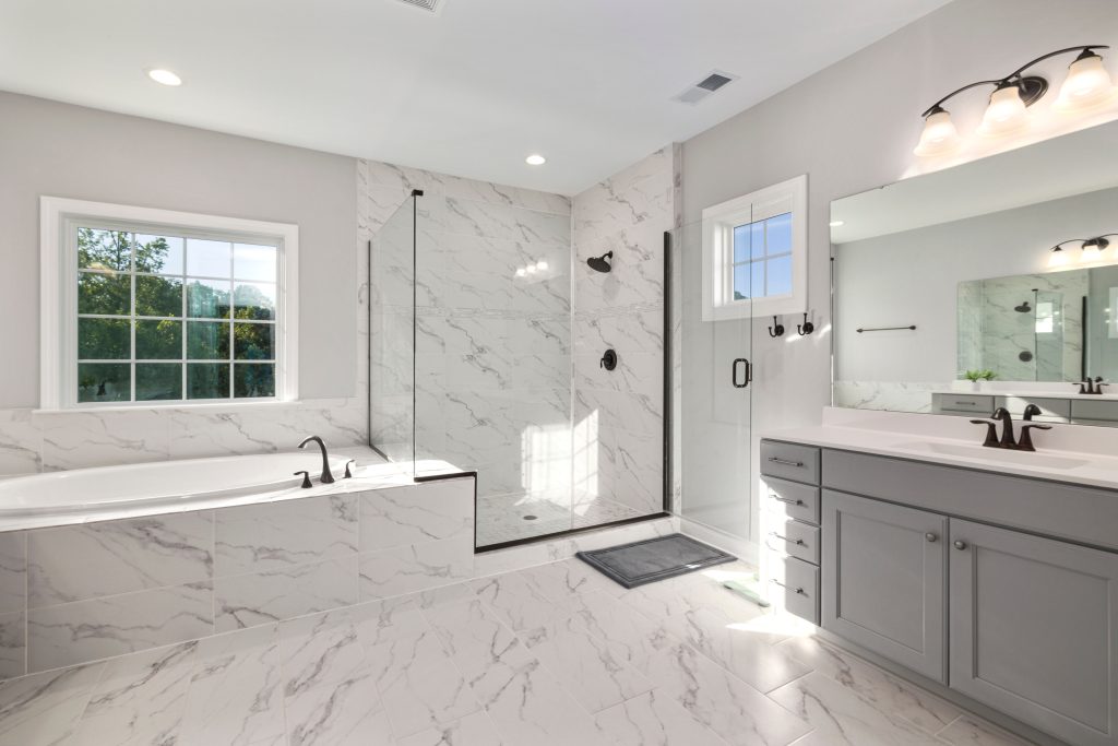 Spacious and elegant bathroom featuring marble tiles, glass shower, and modern vanity.